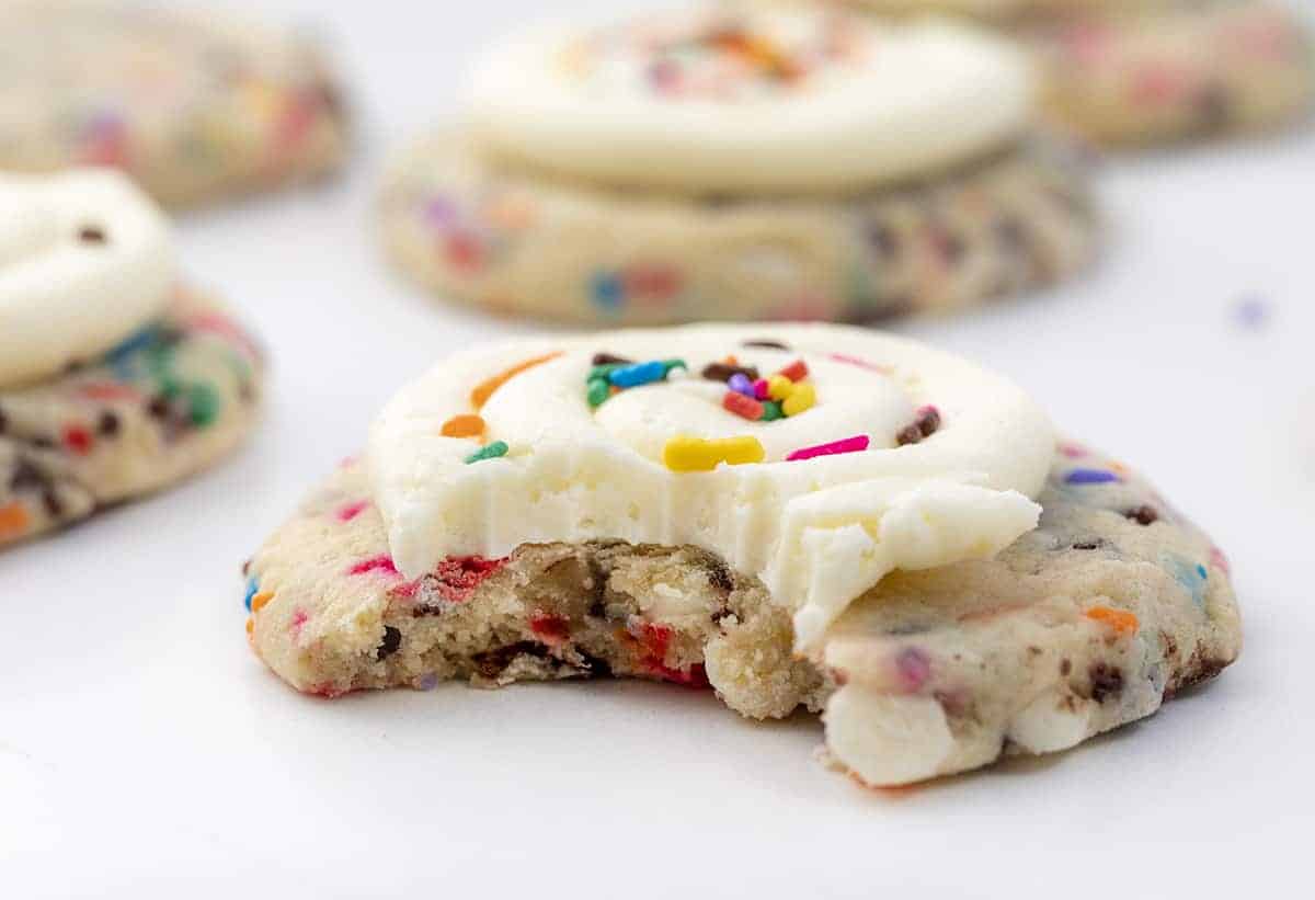 Birthday Cookies are chilled, but soft cookies that are loaded with colorful sprinkles, both chocolate and white chocolate chips, and topped with buttercream frosting. Cookies, Baking, Dessert, Birthday Cookies, Cookies with Frosting, Crumbl copycat cookie, birthday cookie recipes, cookie recipes, i am baker, iambaker Birthday Cake Cookie with a Bite Taken Out of It
