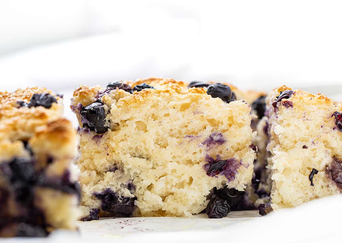Blueberry Butter Swim Biscuits combine the flavors of blueberries, butter, and a hint of sweetness with a moist and fluffy crumb and crispy golden brown top. They can be enjoyed as a breakfast treat, a snack, or even as a dessert! Plus, they are SO EASY to make! Close up of a Blueberry Butter Swim Biscuit Showing Tender Crumb.