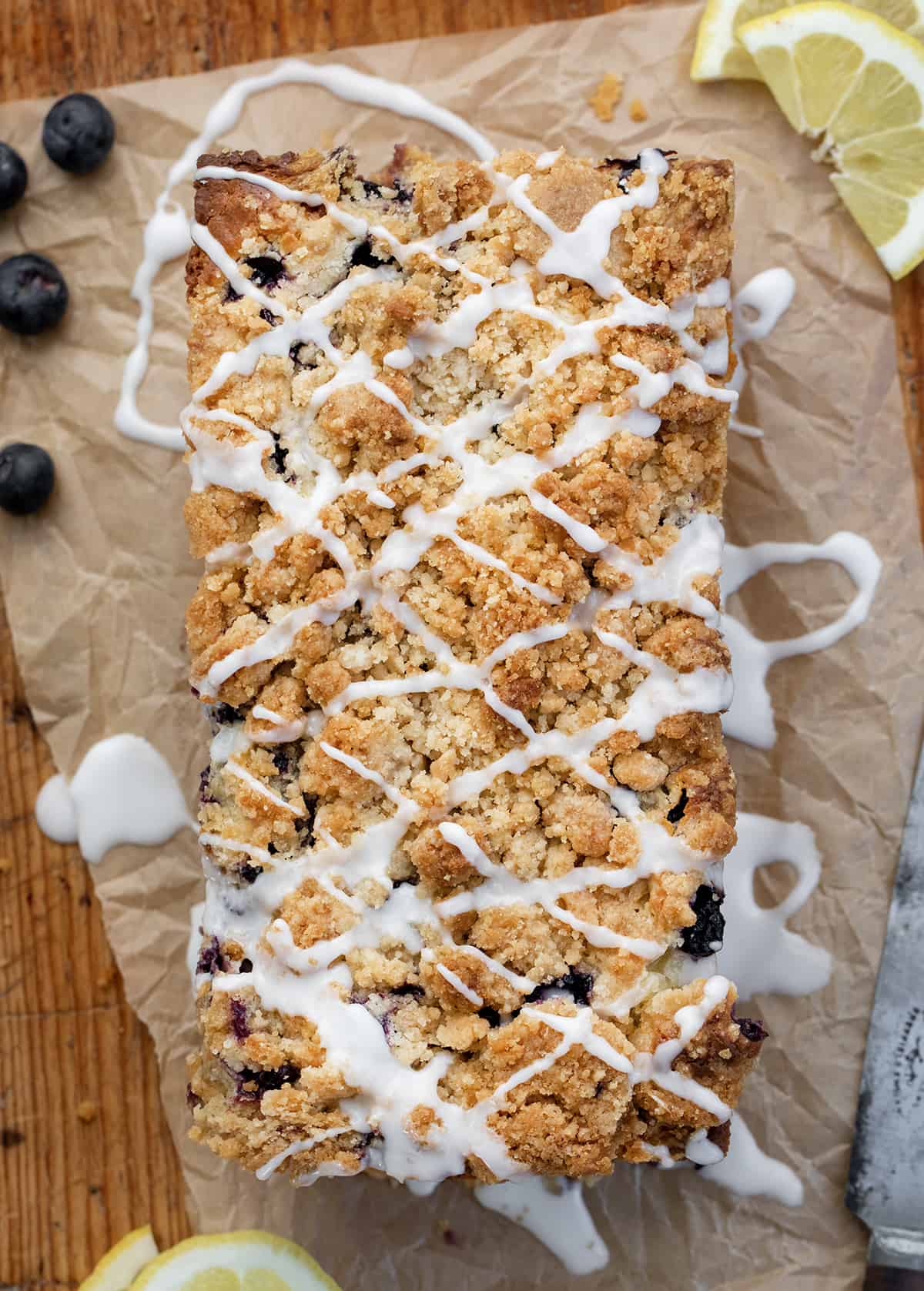 Blueberry Lemon Loaf is a moist cake-like loaf loaded with fresh blueberries and lemon flavor, topped and baked with a crumble topping. Then, the loaf is drizzled with a sweet glaze to make this a perfect breakfast, snack, or dessert. This is a copycat of the viral Costco Blueberry Lemon Loaf and dare I say, even BETTER!! Blueberry Lemon Loaf on a Cutting Board Covered in Glaze Just like Copycat Costco Recipe.