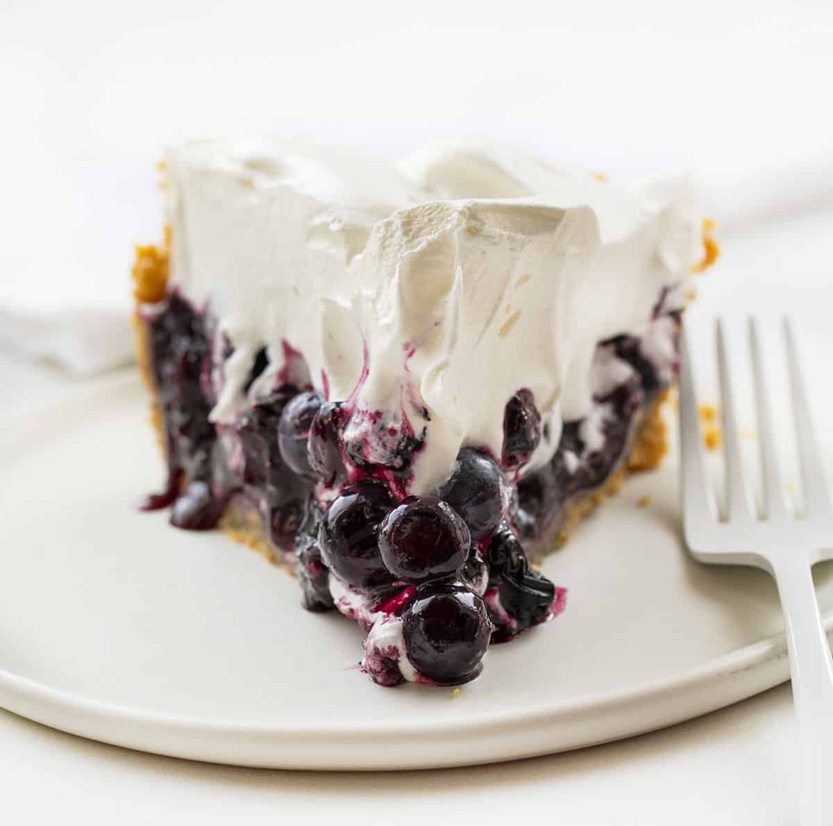 Blueberry Pie {No Bake} is an easy-to-make, refreshing pie made with fresh blueberries over a graham cracker crust topped with whipped topping. BLueberry PIe, Fresh Blueberry Pie, Blueberry Pie with Frozen Blueberries, Pie, Pie Recipes, No Bake Blueberry Pie, Easy Blueberry Pie, Summer PIe, Dessert, BBQ Dessert, no bake dessert, i am baker, iambaker Slice of Blueberry Pie