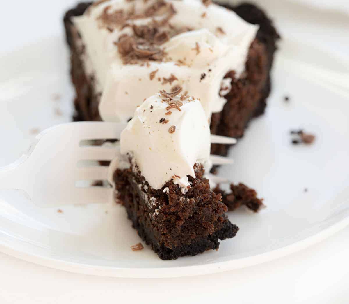 Brownie Pie is a dessert made with an Oreo cookie crust, a layer of chewy brownies, and topped with homemade whipped topping with a drizzle of chocolate syrup. Brownie Pie, How to Make Brownie Pie, the Original Brownie Pie, Brownie Recipe, Pie, Dessert, recipes, baking, i am baker, iambaker Fork Cutting into Brownie Pie Recipe