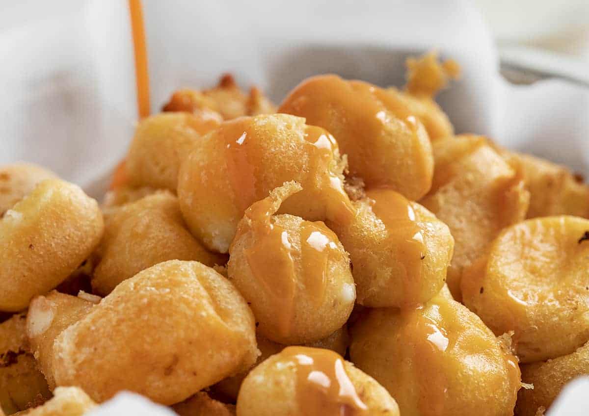 Buffalo Cheese Curds are cheese curds that are breaded in a buffalo-flavored batter using my homemade buffalo sauce and fried to a crisp golden brown. buffalo cheese curds, cheese curds, deep-fried cheese curds, fried cheese curds, white cheddar cheese curds, state fair foods, appetizers, iambaker, i am baker, homemade cheese curds Drizzling Buffalo Sauce over Buffalo Cheese Curds
