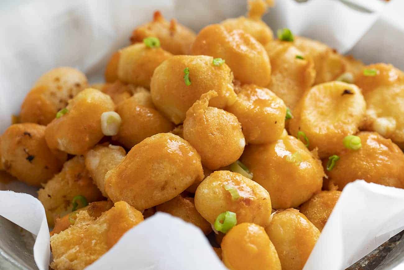 Buffalo Cheese Curds are cheese curds that are breaded in a buffalo-flavored batter using my homemade buffalo sauce and fried to a crisp golden brown. buffalo cheese curds, cheese curds, deep-fried cheese curds, fried cheese curds, white cheddar cheese curds, state fair foods, appetizers, iambaker, i am baker, homemade cheese curds Basket of Buffalo Cheese Curds with Buffalo Sauce and Scallion Sprinkled on Top