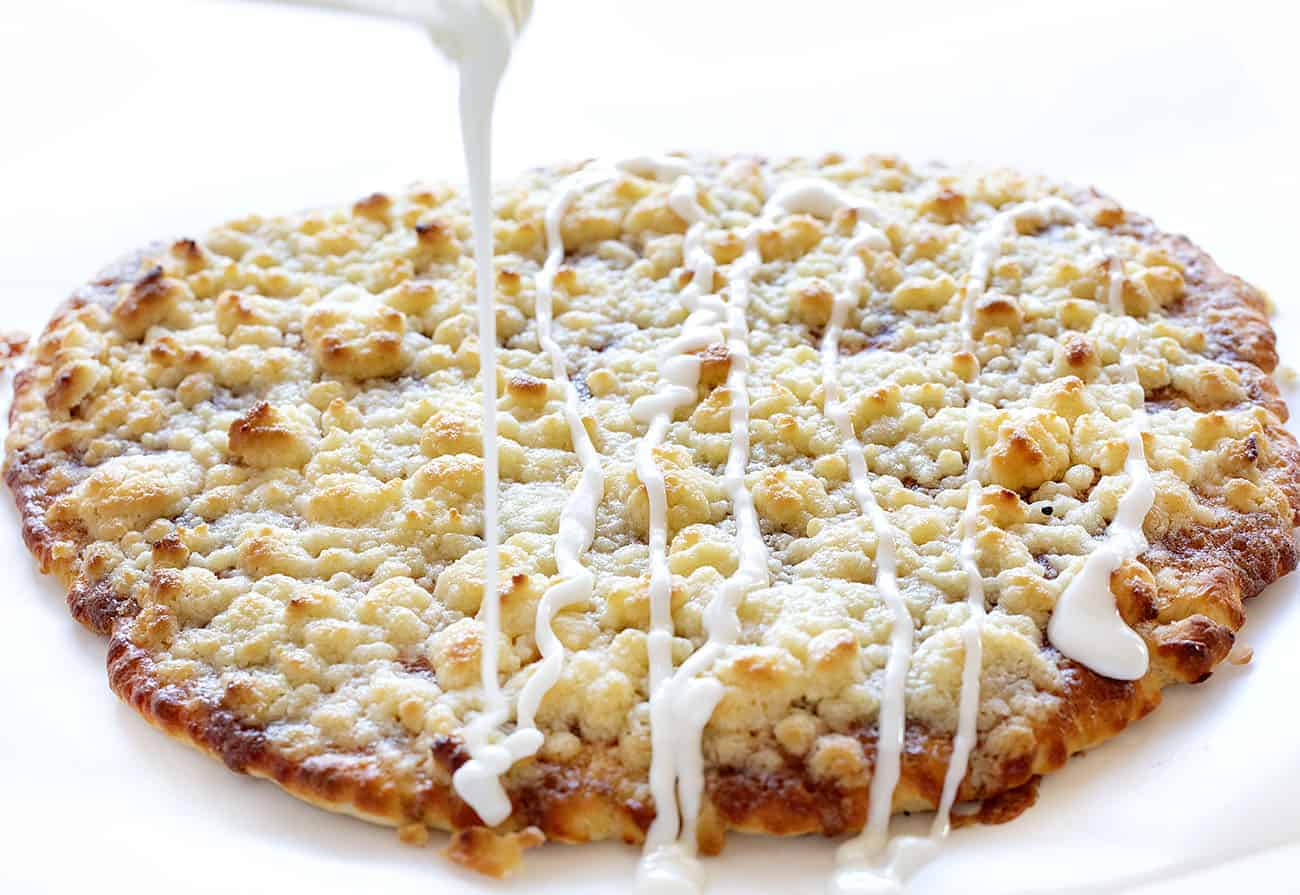 This recipe has been TESTED and PERFECTED! A glorious cinnamon-sugar dessert pizza covered in the best sweet glaze. A fan favorite! cactus bread, copycat cactus bread, dessert pizza, crispy cinnamon dessert, dessert, baking, recipes, iambaker Drizzling Glaze on Warm Cactus Bread