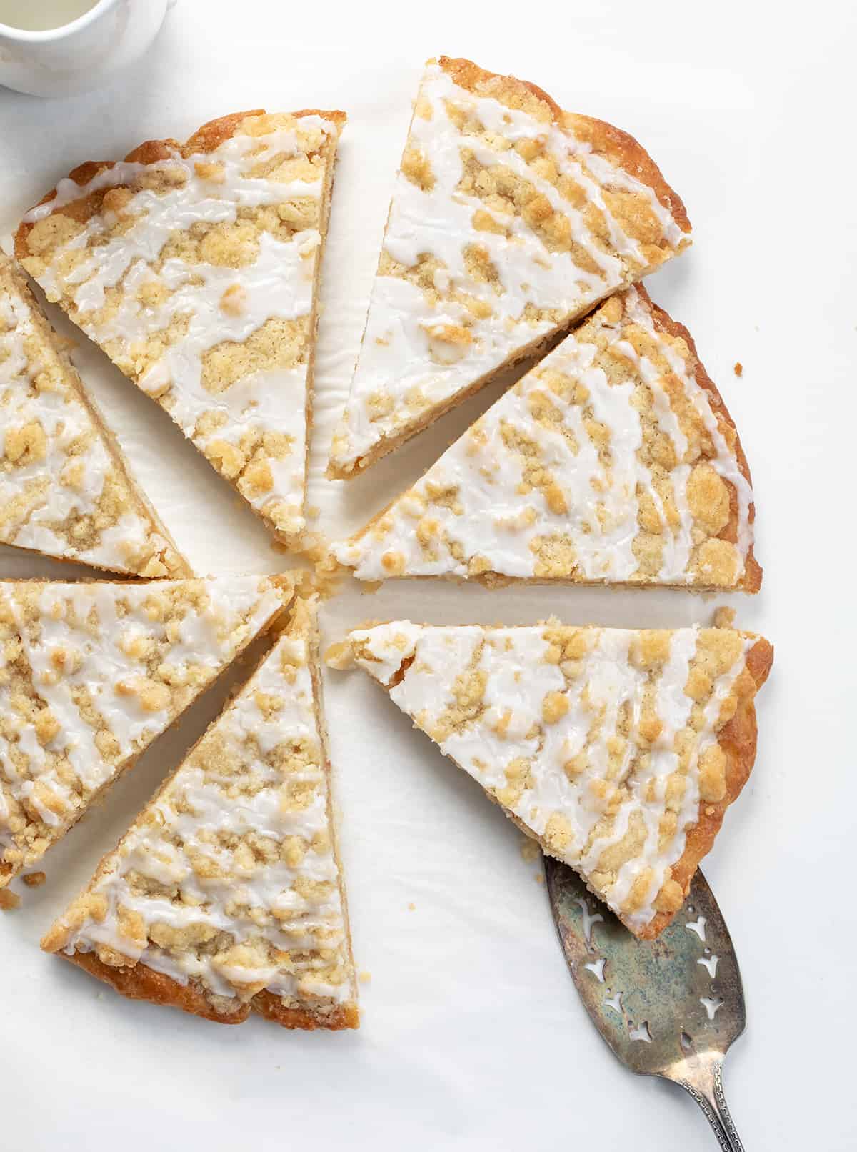 Cactus Bread is a sweet, soft, slightly spiced dessert pizza that folks who go to Pizza Ranch restaurant make a special point to get! The actual Pizza Ranch recipe is a closely guarded secret, but I think this version is just as delicious! It starts with a light and airy focaccia crust topped with cinnamon butter and a delightful crumble topping that will leave everyone craving more! Dessert Pizza (Copycat Cactus Bread) Cut Into Pieces and Separated with One Being Removed with a Utensil.