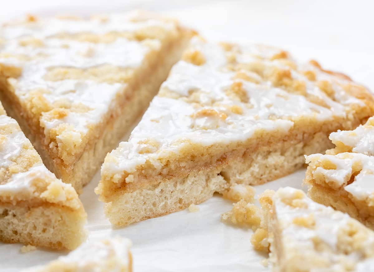 Cactus Bread is a sweet, soft, slightly spiced dessert pizza that folks who go to Pizza Ranch restaurant make a special point to get! The actual Pizza Ranch recipe is a closely guarded secret, but I think this version is just as delicious! It starts with a light and airy focaccia crust topped with cinnamon butter and a delightful crumble topping that will leave everyone craving more! Close up of Cactus Bread Dessert Pizza Showing Soft Crumble Cinnamon Butter and Glaze.