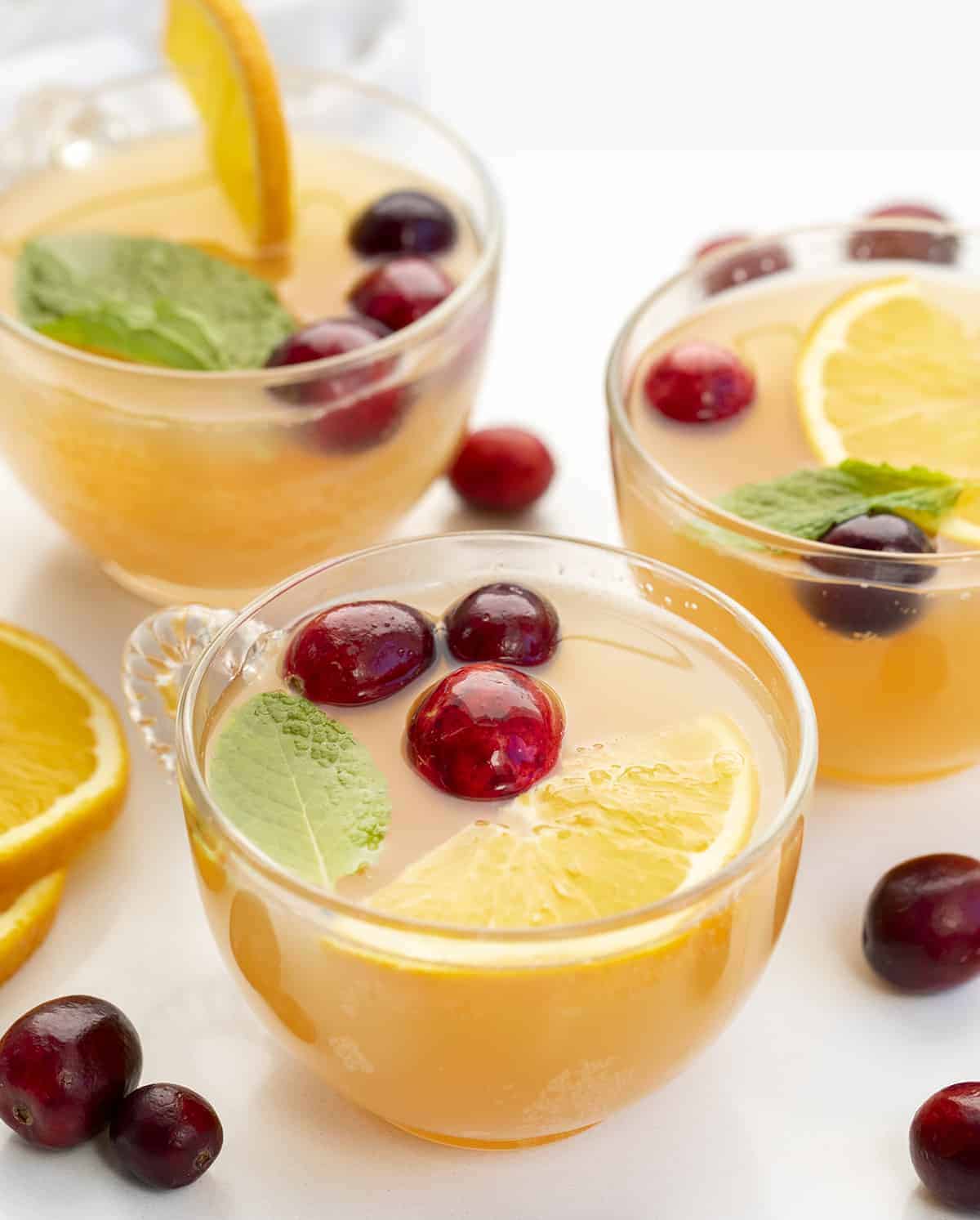 Christmas Punch is a festive and fizzy alcoholic beverage made with orange juice, pineapple juice, cranberry juice, lemon juice, triple sec, rum, and lemon-lime soda. Boozy Punch, Alcohol in Punch, Recipe for Holiday Punch, holiday drink recipes, i am baker, iambaker Cups of Christmas Punch