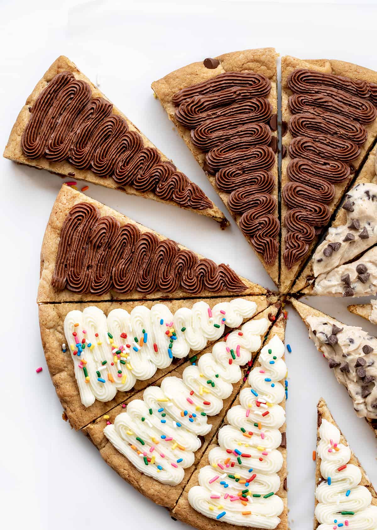 Cookie Cake For A Crowd is a colossal chocolate chip cookie frosted in three sections with cookie dough frosting, whipped chocolate buttercream, and American buttercream. The cookie itself has a soft and tender texture that is delightful on its own. Then, the frosting adds an extra layer of indulgence! It's like three treats in one! Cookie Cake for a Crowd with Chocolate Frosting, Vanilla Frosting, and Cookie Dough Frosting.