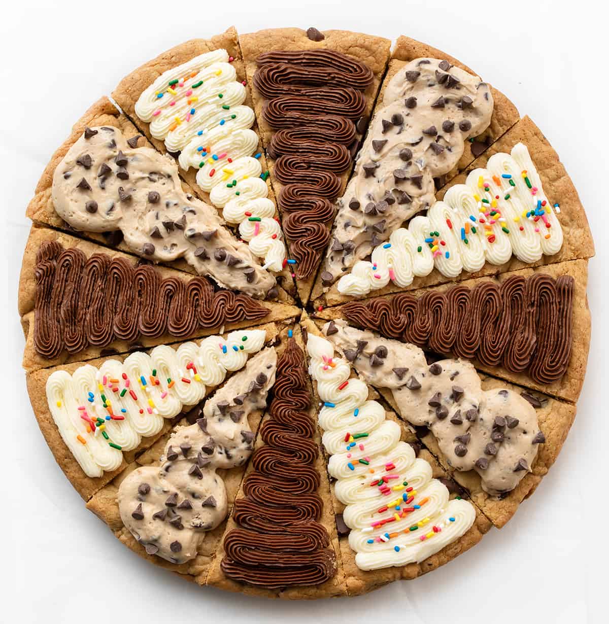 Cookie Cake For A Crowd is a colossal chocolate chip cookie frosted in three sections with cookie dough frosting, whipped chocolate buttercream, and American buttercream. The cookie itself has a soft and tender texture that is delightful on its own. Then, the frosting adds an extra layer of indulgence! It's like three treats in one! Cookie Cake for a Crowd with Chocolate Frosting, Vanilla Frosting, and Cookie Dough Frosting.