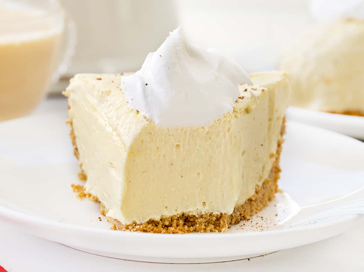 No-Bake Eggnog Pie is a creamy pie made with vanilla pudding mix, nutmeg, eggnog, rum, and whipped cream that tastes just like a glass of eggnog! Pie, No Bake Pie, Eggnog Pie, Leftover Eggnog Recipes, How to Use Eggnog, Graham Cracker Crust Pie, Dessert, Easy Pie, New Years Pie, i am baker, iambaker Slice of Eggnog Pie with Bite Removed