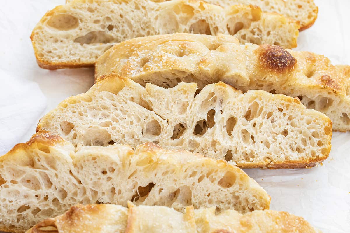 Sourdough Focaccia is fluffy and chewy on the inside with a crispy outside, made with an active sourdough starter for that sourdough flavor in every bite! It is delicious on its own, but also pairs wonderfully with various spreads and dipping options. Plus, it is made in a baking dish with just a few ingredients and no yeast. If you have a little patience, you can certainly make this bread. Close up of Sourdough Focaccia After it Has Been Cut Into Pieces.