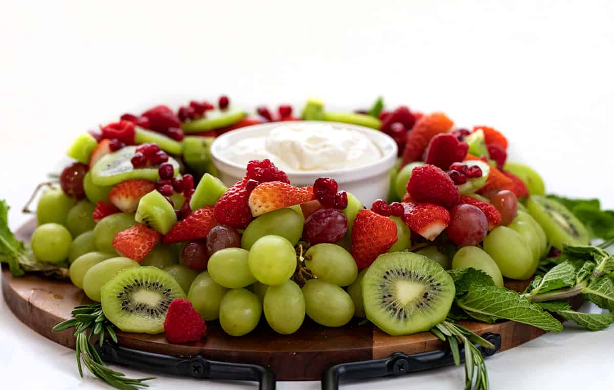 Holiday Wreath Fruit Tray is a beautiful and colorful display of fruit and herbs in a circular design with fruit dip in the center for serving. The fruit tray is presented to represent a wreath, a popular symbol of Christmas. Be sure to add this to your holiday menu! Side View of a Holiday Wreath Fruit Tray.