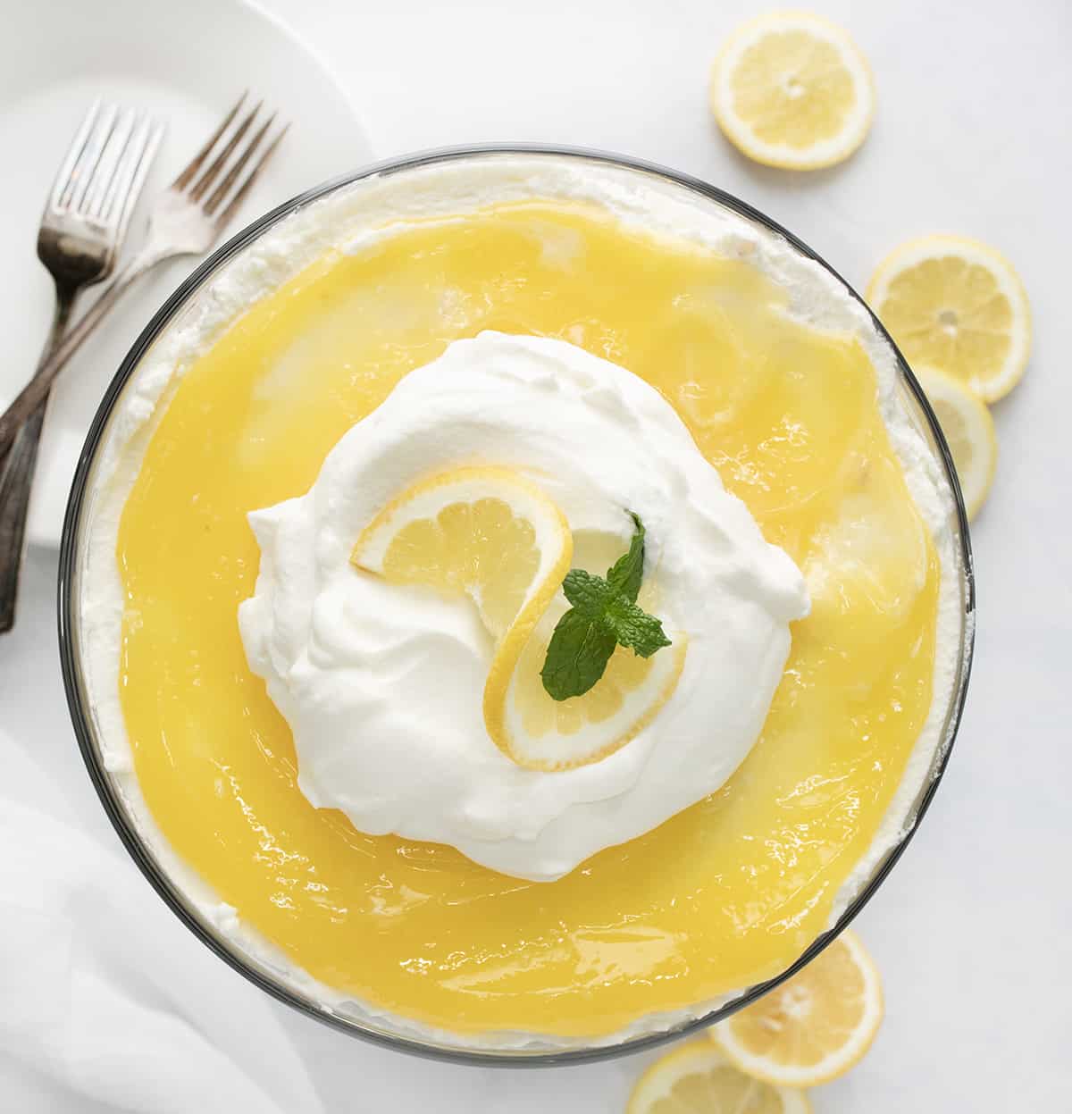 Lemon Cream Trifle is a layered dessert made with cubes of angel food cake, whipped cream, and homemade lemon curd. Each refreshing and indulgent bite is full of lemon flavor with a lovely blend of textures. If you love lemon desserts, you will definitely want to keep the lemon curd recipe on hand for more desserts and treats! Overhead of a Lemon Cream Trifle, Looking Down on the Lemon Curd.