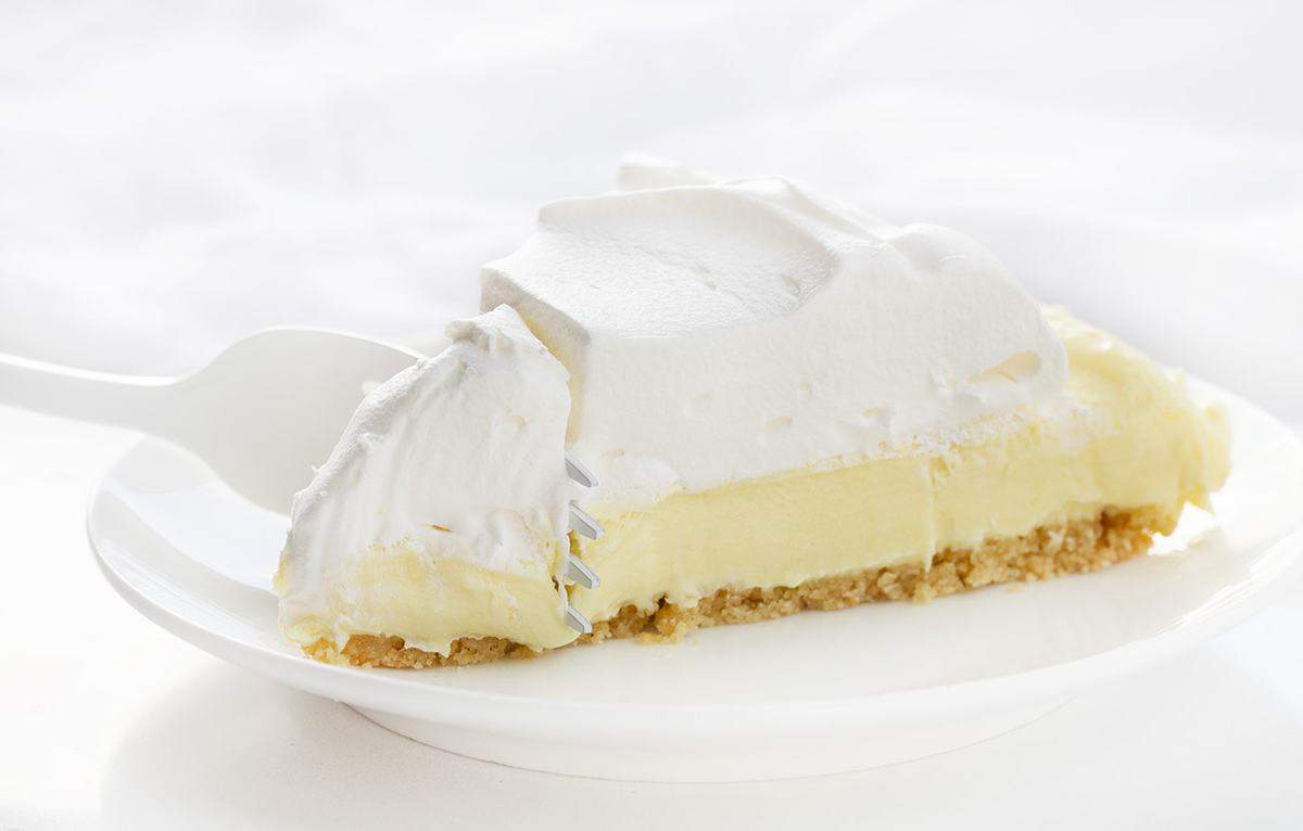 Lemonade Pie is a no-bake dessert that is as delicious and refreshing as a tall glass of lemonade on a hot summer day. iambaker, lemonade pie, no-bake desserts, summer desserts, lemonade, pie recipes, i am baker, cream pie, recipes, dessert Fork Cutting into one Piece of Lemonade Pie