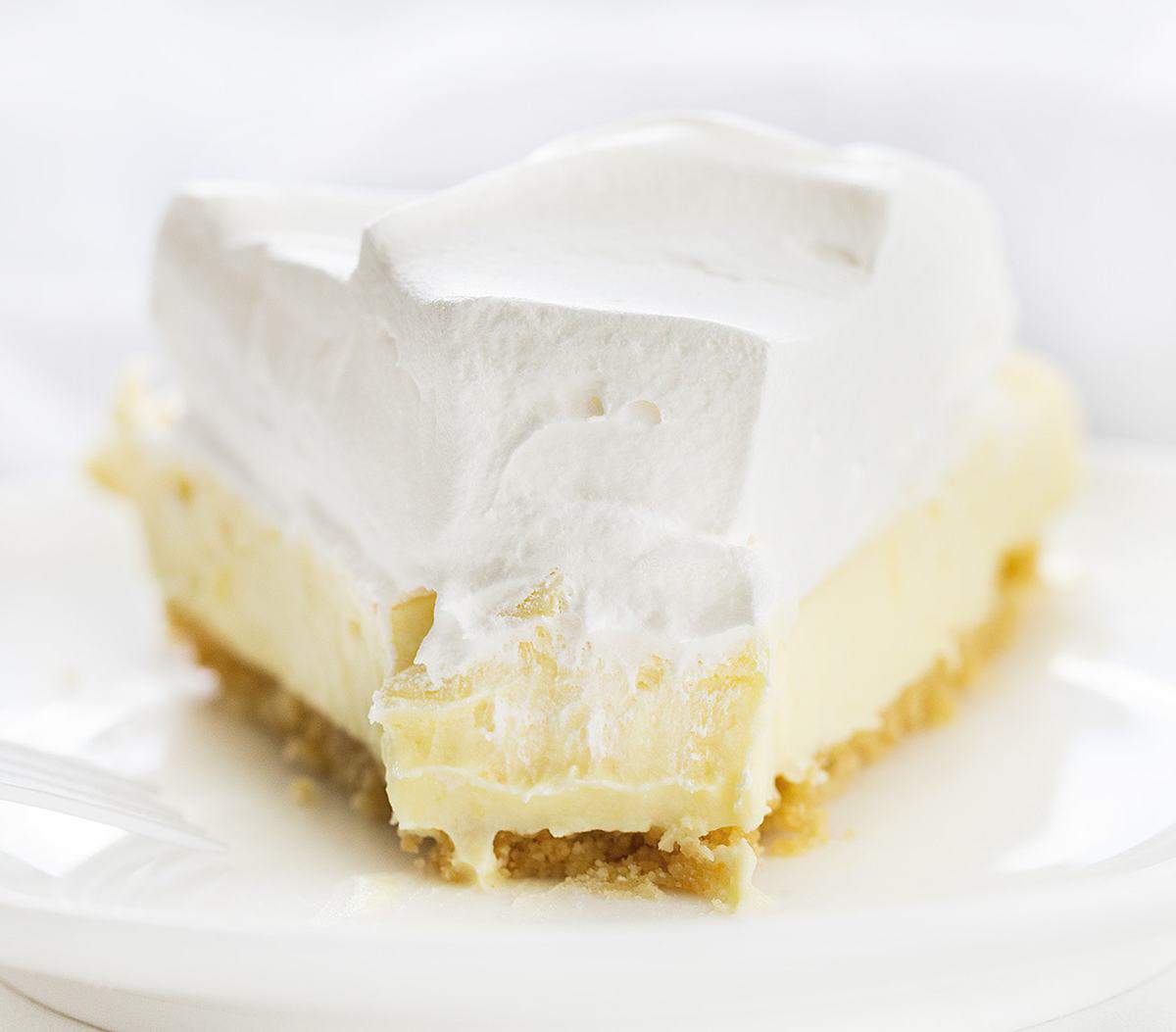 Lemonade Pie is a no-bake dessert that is as delicious and refreshing as a tall glass of lemonade on a hot summer day. iambaker, lemonade pie, no-bake desserts, summer desserts, lemonade, pie recipes, i am baker, cream pie, recipes, dessert One Piece of Lemonade Pie with a Bite Missing and Fork Resting on Plate