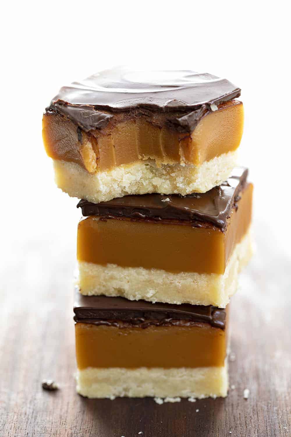 Millionaire's Bars are a sweet, layered dessert made with a shortbread crust, caramel filling, and a semi-sweet chocolate topping. Millionaire Bars, How to Make Millionaire Bars, The Best Millionaire Bars, Billionaire Bars, Bars, Dessert, Recipes, Chocolate, Caramel, Soft Caramel, i am baker, iambaker Stacked Millionaire Bars with One Bitten