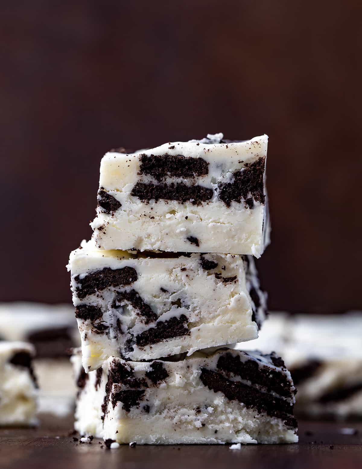 Cookies and Cream Fudge is an easy-to-make treat with white chocolate chips, marshmallow fluff, and Oreo cookies. It should definitely be added to your list of holiday treats this season! Stack of Cookies and Cream Fudge on a Dark Cutting Board.