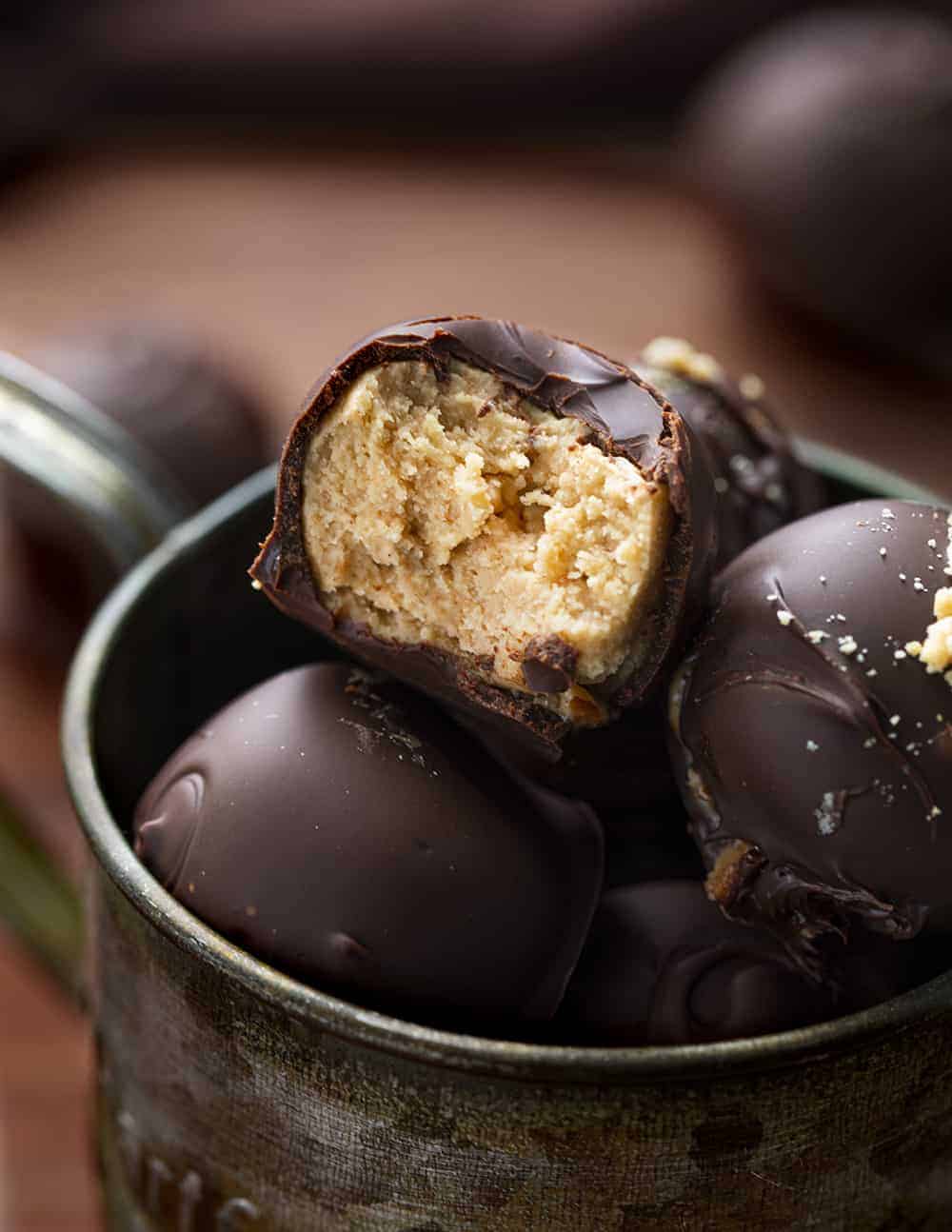 Peanut Butter Balls are sweet treats that are made with creamy peanut butter and coated with a layer of melted, semi-sweet chocolate. PeanutButter Balls, PB Balls recipes, Christmas Candy, Candy, recipes, Peanut Butter Balls Recipes, How to Make PB Candy, iambaker, i am baker Bit Into Peanut Butter Ball Showing Inside