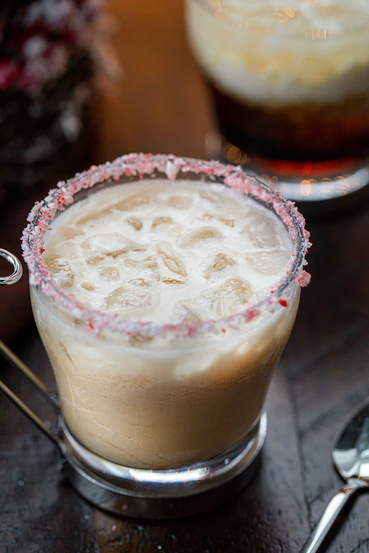 This alcoholic beverage gives a peppermint and festive twist to a White Russian cocktail. It still contains Kahlua, vodka, and cream. But then has added peppermint schnapps to give it a minty twist. And, don't forget about the crushed candy cane around the rim of the glass. That will really be a lovely touch if serving at your Christmas or New Year's Eve parties. Peppermint White Russians in front of a Christmas Tree and Twinkling Lights.