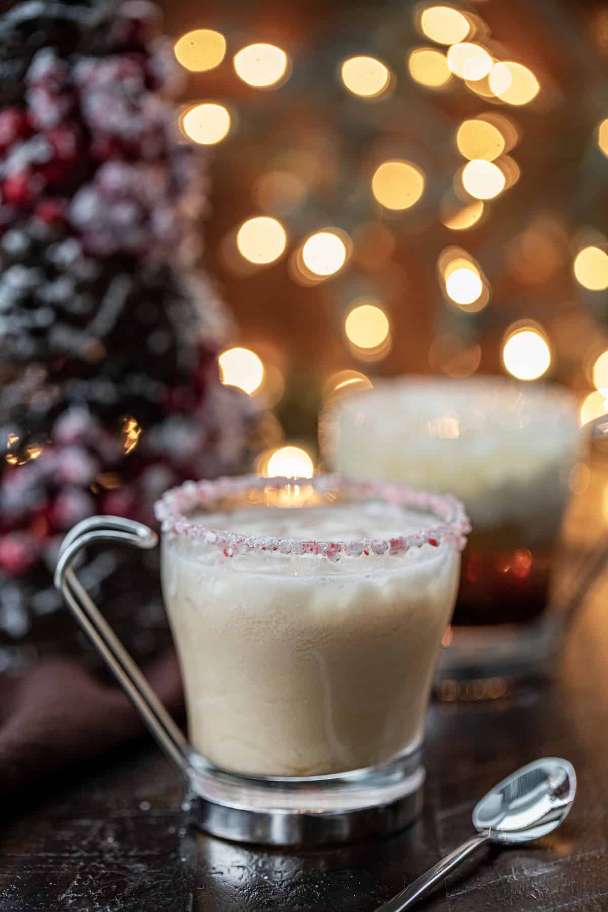 This alcoholic beverage gives a peppermint and festive twist to a White Russian cocktail. It still contains Kahlua, vodka, and cream. But then has added peppermint schnapps to give it a minty twist. And, don't forget about the crushed candy cane around the rim of the glass. That will really be a lovely touch if serving at your Christmas or New Year's Eve parties. Peppermint White Russians in front of a Christmas Tree and Twinkling Lights.
