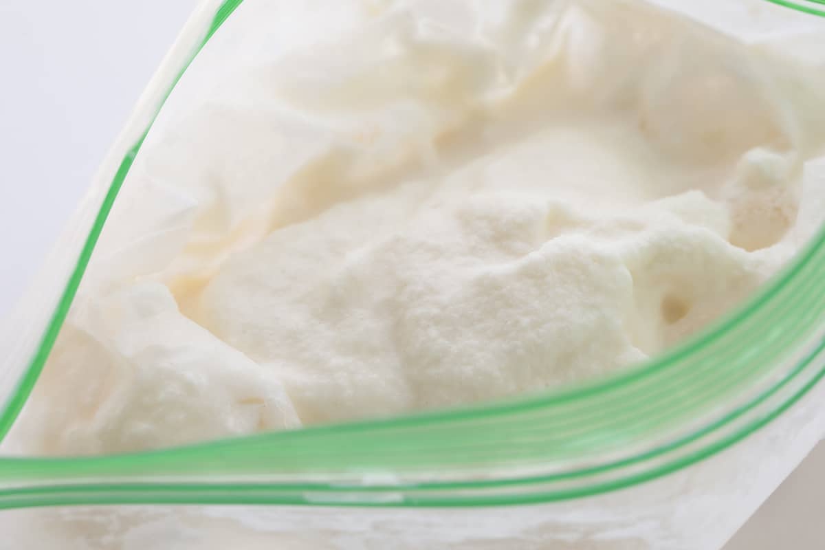 Quick and Easy Soft Serve Ice Cream (also known as small batch ice cream in a bag!)is smooth and creamy vanilla ice cream made with no special equipment and ready in about 5 minutes! All you need is a little arm strength, and then the ice cream will be ready to enjoy! This is a wonderful recipe for kids to be involved! Close up of Soft Serve Ice Cream in a Plastic Bag After Shaking it in a Salt and Ice Bag.