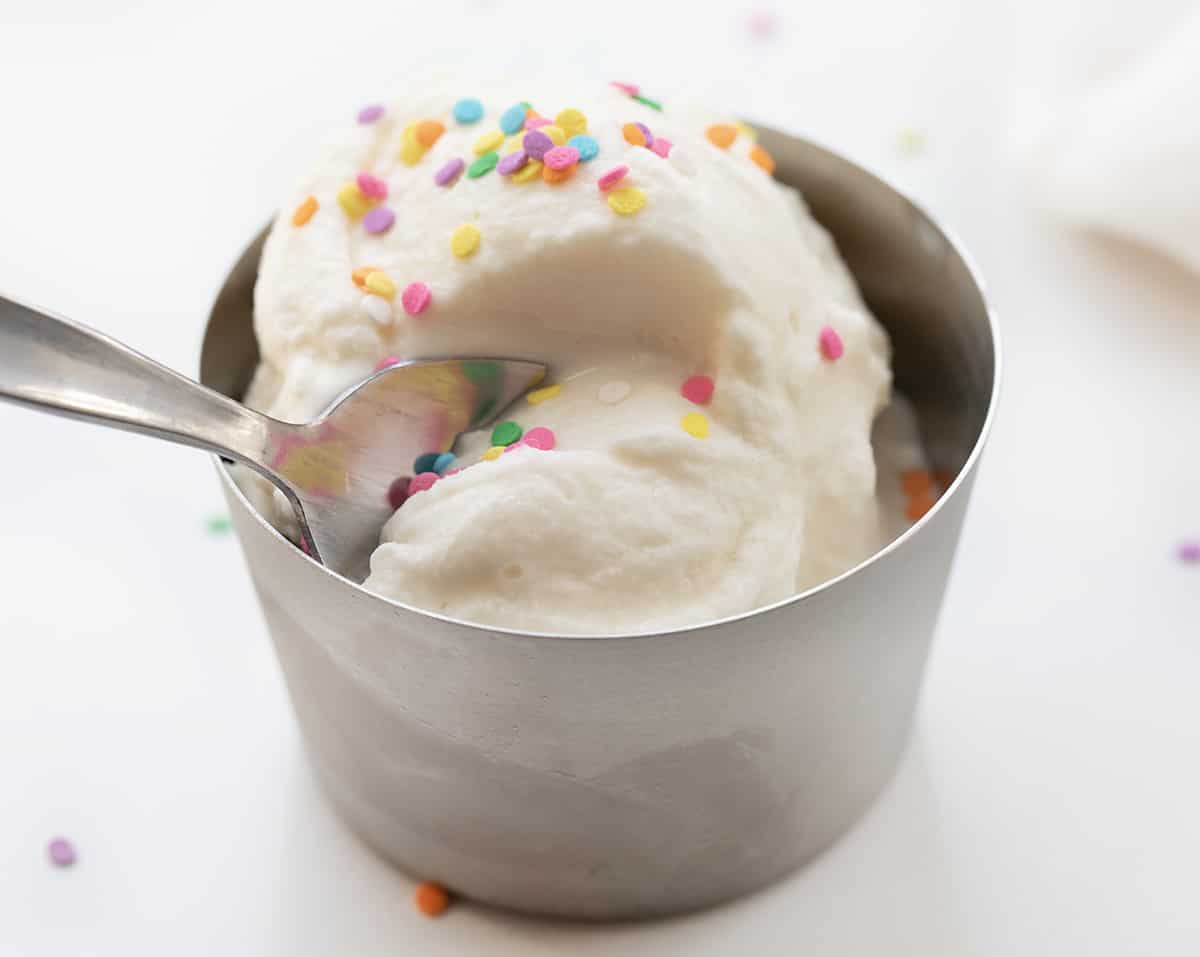 Quick and Easy Soft Serve Ice Cream (also known as small batch ice cream in a bag!)is smooth and creamy vanilla ice cream made with no special equipment and ready in about 5 minutes! All you need is a little arm strength, and then the ice cream will be ready to enjoy! This is a wonderful recipe for kids to be involved! Spoon Taking a Bite out of a Metal Dish with Soft Serve Ice Cream.