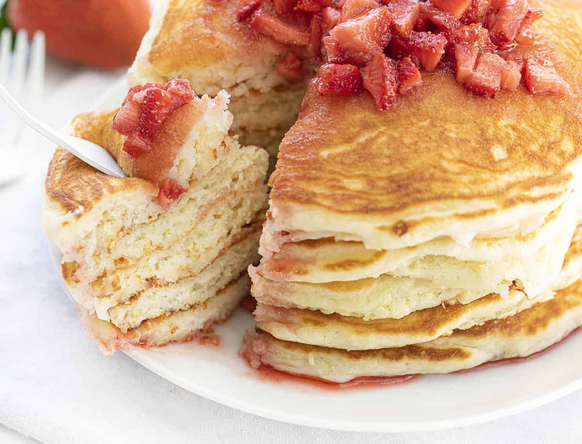 Strawberry Cheesecake Pancakes are fluffy buttermilk pancakes with a cream cheese swirl inside and topped with strawberry syrup. Pancakes, Strawberry Cheesecake Pancakes, Cheesecake Pancakes, Breakfast, Buttermilk Pancakes, Best Pancake Recipe, i am baker, iambaker, recipes Fork Taking Bite from Strawberry Cheesecake Pancakes