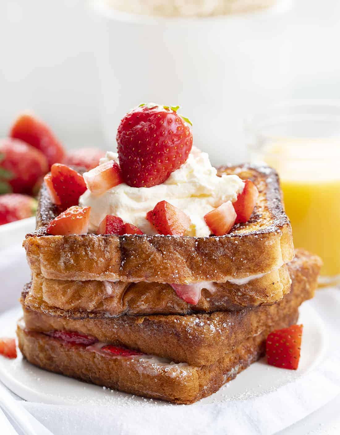 Stuffed French Toast is covered with a cinnamon and sugar coating and filled with cream cheese and juicy strawberries, topped with confectioners’ sugar and whipped cream. Stuffed French Toast, How to Make Stuffed French Toast, Stuffed French Toast Recipe, Breakfast, French Toast, Recipes, i am baker, iambaker Strawberry Stuffed French Toast on a Plate