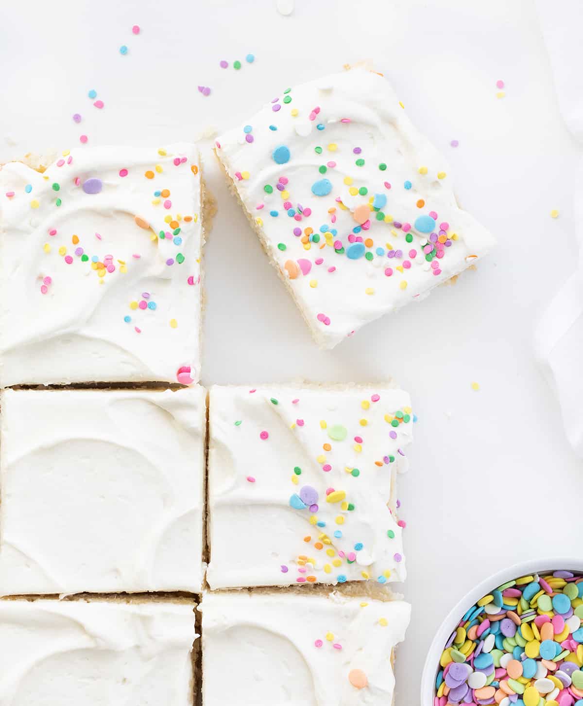 Vanilla Delight Cake (or white cake) is a moist, delicate, and flavorful white sheet cake that is delicious on its own or perfect for your favorite frostings and toppings. It is definitely delightful to snack on, enjoy as a dessert, or share at your next celebration or party! Pieces of Vanilla-Delight Cake or White Cake on a Counter with Pastel Colored Sprinkles.