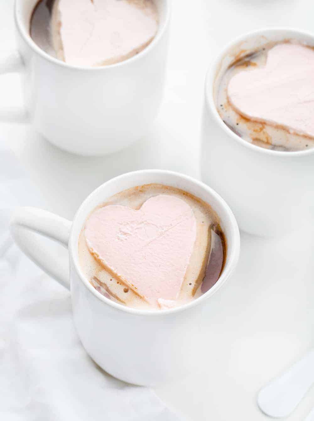 Whipped Cream Hearts are made with a homemade whipped topping that has been frozen and cut into heart shapes. Whipped Cream Hearts, Valentines Day, Dessert, Frozen Whipped Cream for Hot Chocolate, Frozen Whipped Cream, homemade whipped cream, i am baker, iambaker, recipes, hot chocolate, hot cocoa ideas Three Mugs with Whipped Cream Heart for Hot Chocolate