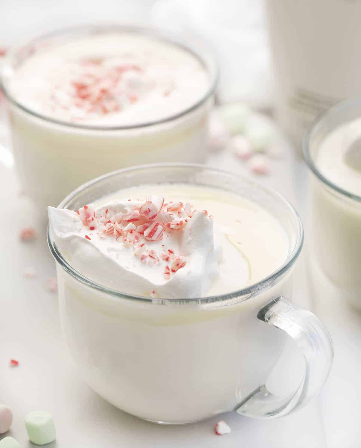 Snowed-in White Hot Chocolate Cocktail is an adult beverage made in a slow cooker with white chocolate, whipping cream, milk, vanilla, and RumChata. Hot Chocolate, Hot Cocoa, Boozy Hot Cocoa, Adult Hot Chocolate, White Chocolate Hot Chocolate, Rumchata Hot Cocoa, beverages, drinks, boozy drinks, winter drinks, i am baker, iambaker Glassed of White Chocolate Hot Cocoa with Whipped Cream and Candycanes